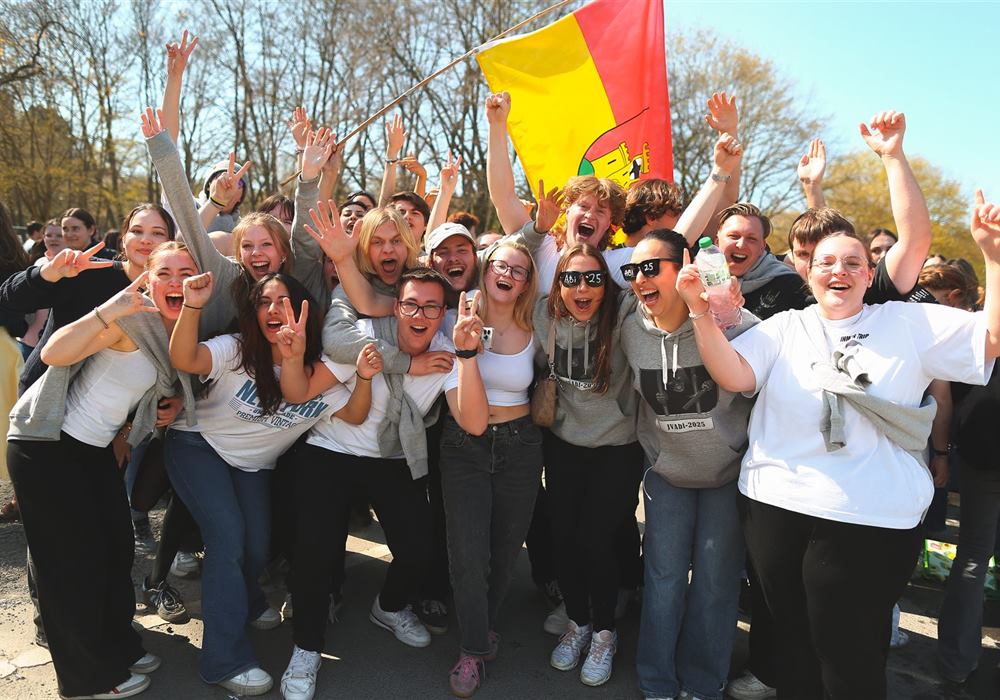 Jubelnde Abiturientinnen und Abiturienten mit Fahne beim Open-Air-Festival