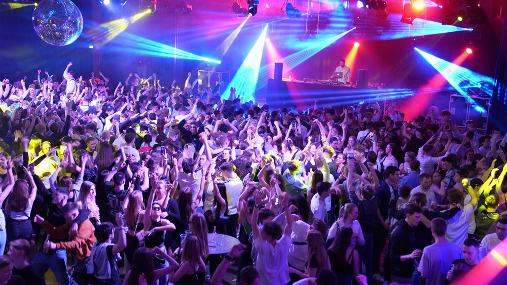 Überblick über die volle Halle mit Lichtshow und tanzender Menge